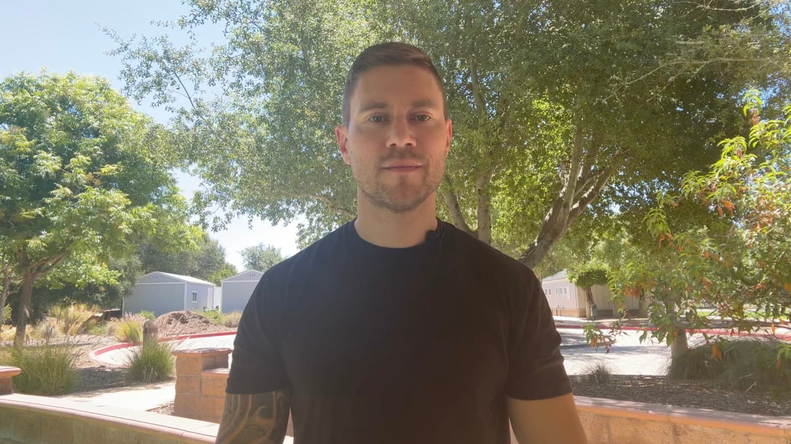 Laurence Larsen wearing a black T-shirt outdoors, from his Tip Top Fitness introduction video